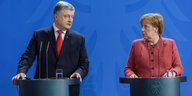 Petro Poroschenko und Angela Merkel stehen an Rednerpulten und gucken sich gerade an.
