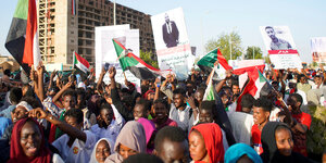 Menschen mit sudanesischen Flaggen und Plakaten demonstrieren in Khartum