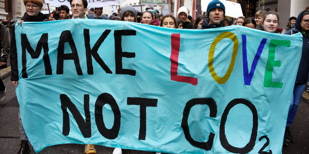 Demonstranten tragen ein Transparent, auf dem steht: „make love not CO2“