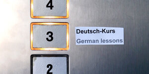 Knöpfe in einem Aufzug, der 3. Stock ist mit einem Zettel "Deutsch-Kurs" markiert