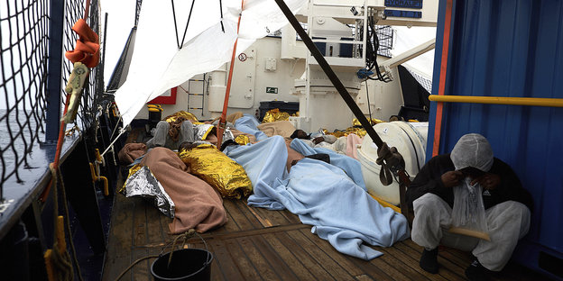 Menschen liegen aneinandergedrängt auf dem Deck eines schiffes