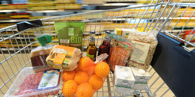 Bioprodukte in einem Einkaufswagen, der an Supermarktregalen vorbeirollt