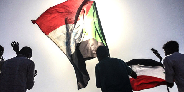 Sudanesische Demonstrierende laufen mit ihrer Flagge herum