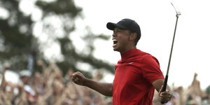 Tiger Woods freut sich, er hält einen Golfschläger in die Höhe