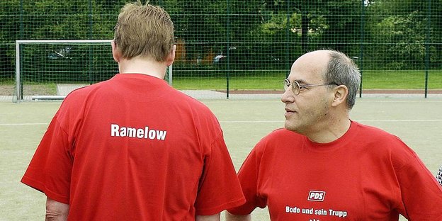 Gregor Gysi und Bodo Ramelow in roten Trikots - Ramelow steht auf dem Fußballplatz mit dem Rücken zur Kamera