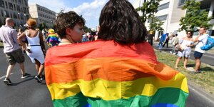 Zwei Frauen hüllen sich in eine Regenbogen-Fahne