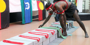 Ein Mann beugt sich über einen Karton mit den sterblichen Überresten der australischen Ureinwohner*innen.