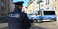 Polizist steht vor Polizeiauto bei Razzia in Cottbus