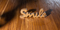 der aus Holz ausgesägte Schriftzug „Smile“