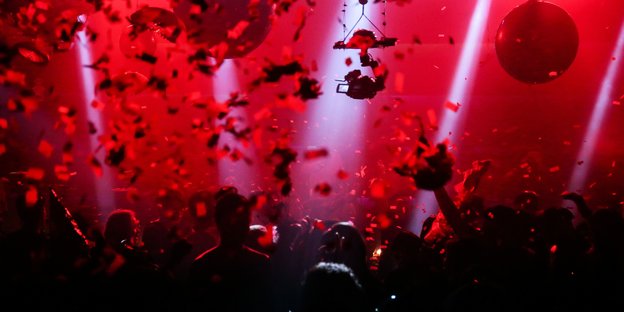 Mehrere Menschen feiern in einem Club - Foto mit Rotfilter