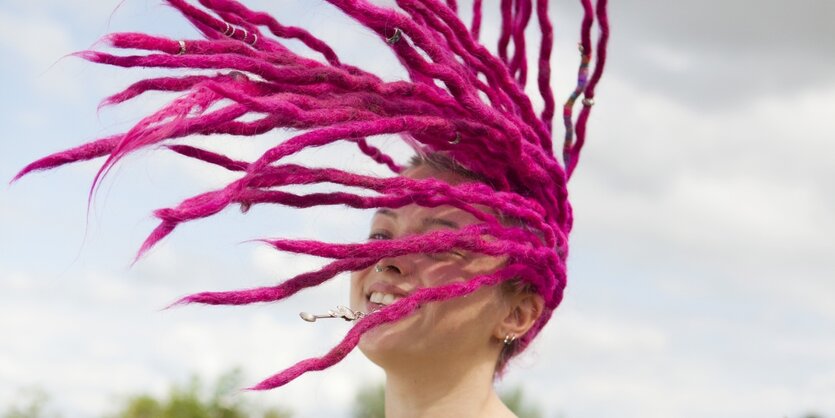 Eine weiße junge Frau mit pinken Dreadlocks