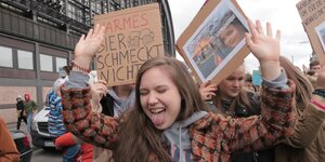 Schülerin reißt die Arme in die Luft, im Hintergrund Fridays-for-Future-Demo