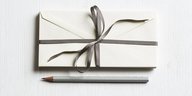Ein Stapel mit Geschenkband eingewickelter Briefe liegt über einem Bleistift