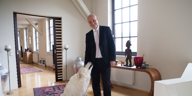 Ein Mann mit einem weißen Hund in einem hellen Raum
