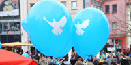 Zwei blaue Luftballons mit aufgedruckten weißen Tauben