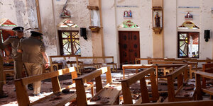 Polizisten stehen in einer zerstörten Kirche