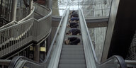 Menschen kauern auf einer Rolltreppe