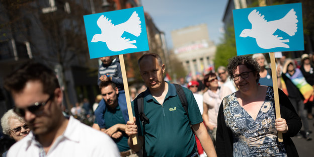 Zwei Demonstranten beim Berliner Ostermarsch tragen Plakate mit einer Friedenstaube