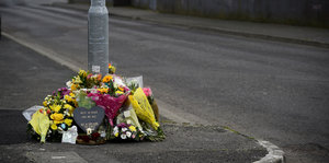 Blumen und eine Kerze liegen auf der Straße, auf der die Journalistin Lyra McKee erschossen wurde