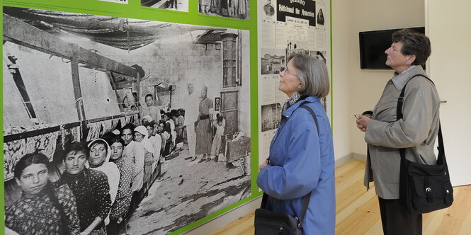 Besucher stehen in einer Ausstellung for Fotografien