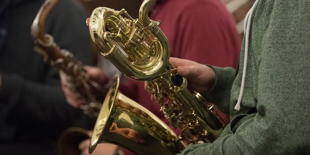 Zwei Menschen halten jeweils ein Saxofon vor sich in ihren Händen.