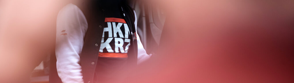 Ein Mensch trägt ein Shirt mit den Buchstaben "HKNKRZ", für Hakenkreuz