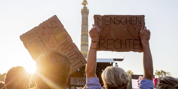 „Menschenrechte" und „Solidarität" steht bei der Abschlusskundgebung der Demonstration gegen Rassismus und Rechtsruck mit dem Motto «Unteilbar» vor der Berliner Siegessäule auf zwei Schildern.