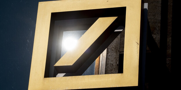 Gelbes Logo der deutschen Bank, darauf spiegelt sich die Sonne