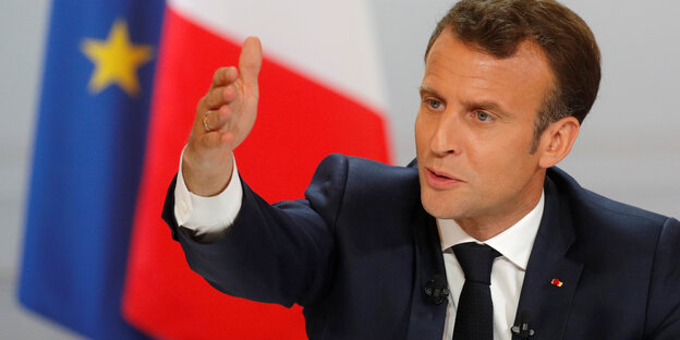 Emmanuell Macron mit erhobener Hand
