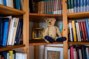 Ein Bücherregal in dem neben Büchern auch ein Teddy sitzt