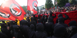 schwarz gekleidete und vermummte Menschen demonstrieren mit Antifa-Fahnen in Kreuzberg