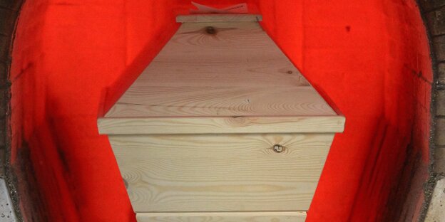 Ein Holzsarg, der ins Krematorium geschoben wird