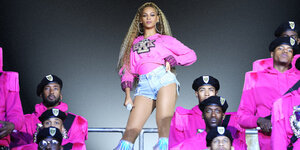 Die Sängerin Beyoncé posiert auf der Bühne in pinkem Dress