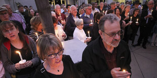 Trauernde Menschen mit Kerzen in einer Kirche