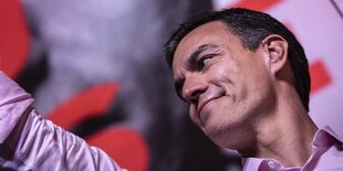 Pedro Sanchez steht auf einer Bühne und winkt