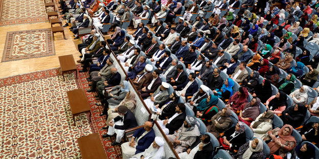 Viele Menschen sitzen auf Stühlen während der großen Ratsversammlung („Loja Dschirga“)