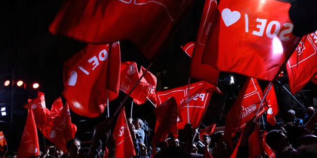 Anhänger der sozialistischen Partei (PSOE) warten vor der Parteizentrale auf die ersten Ergebnisse und schwenken Fahnen