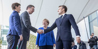 Frankreichs Staatschef Emmanuel Macron begrüßt mit einem überschwänglichen Handschlag Aleksandar Vucic (2.v.l.), Staatspräsident von Serbien. Dahinter steht Angela Merkel.