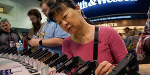 Eine Frau schaut sich ausgestellte Handfeuerwaffen an.