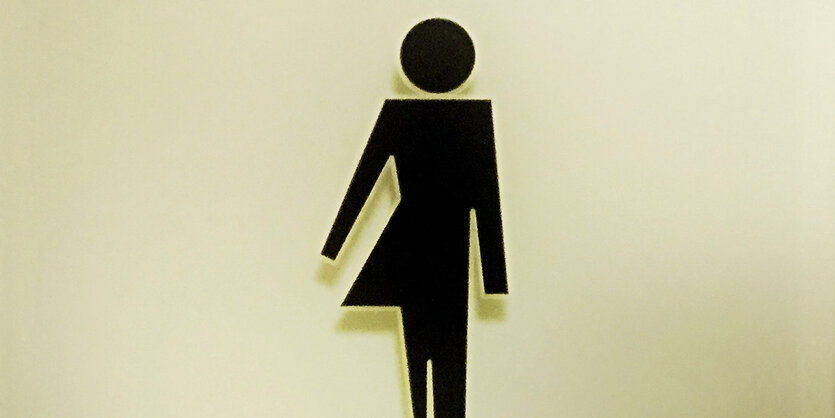 Ein Unisex-Toilettenschild zeigt zur einen Hälfte eine Silhoutte mit Rock, zur anderen Hälfte eine Silhoutte ohne Rock