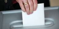 Hand wirft Umschlag in eine Wahlurne