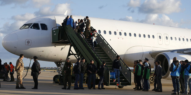 Eine Flugzeug steht auf Landebahn, Leute steigen über eine Treppe aus
