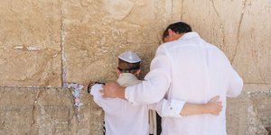 Ein Vater und sein Sohn beten an der Klagemauer