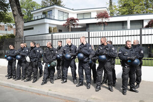 Mehrere Polizisten stehen in einer Reihe vor dem Zaun einer großen Villa Mehrere Polizisten stehen in einer Reihe vor dem Zaun einer großen Villa
