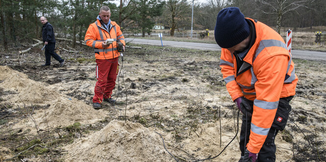 Zwei Personen in Warnwesten arbeiten im Sand