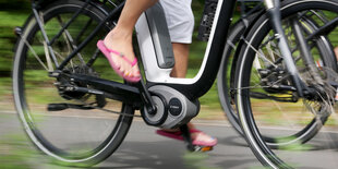 Eine Frau fährt in Schlappen auf einem E-Bike