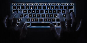 Ein Mann benutzt die beleuchtete Tastatur eines Notebooks