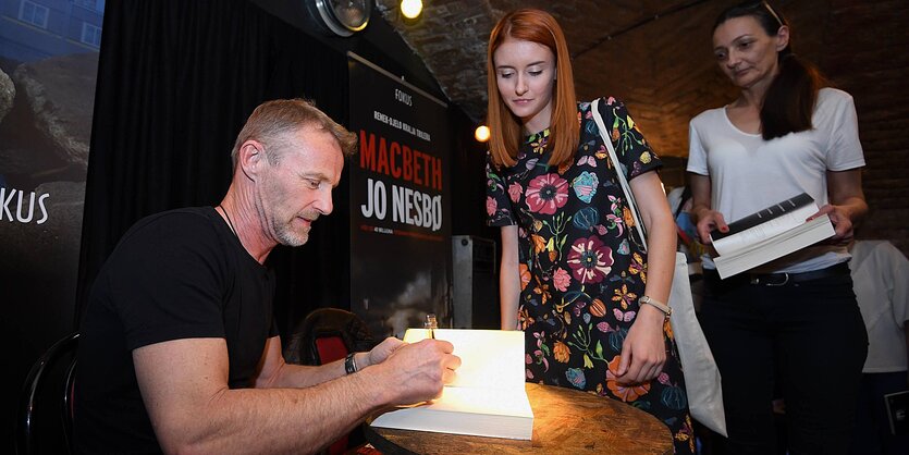 Der Schriftsteller Jo Nesbo gibt einer Leserin ein Autogram in sein Buch