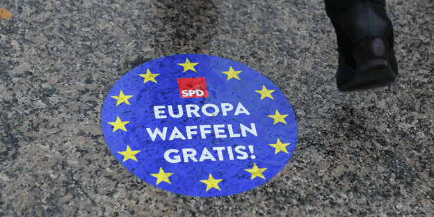 Jemand läuft über einen SPD-Wahlwerbeaufkleber mit der Aufschrift: "Europa Waffeln gratis"