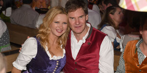 Carsten Maschmeyer sitzt mit seiner Frau Veronica Ferres auf dem Oktoberfest an einem Tisch. Sie lächeln in die Kamera